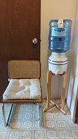 Photo of the chair and water cooler next to a closed door on linoleum flooring with floral pattern.