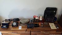Full lot overview with items arranged on table including hats, watches, clocks, bags, pocket cutters, remote control and other items