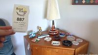 Photo showing the full lot arranged on a wood surface including matches, lighters, ashtrays, playing cards, and the lamp base with shade.