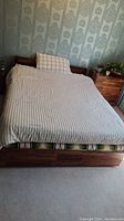 Front view of queen size wooden bed with bedding and pillow