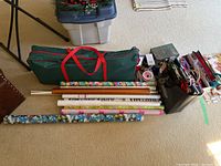 Photo showing large green fabric carrying bag, several rolls of gift wrap paper on the floor, and gift bags.