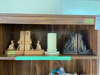 Shelf with three pairs of bookends including carved wood, marble, and metal