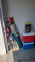 Wide view of all items showing 2 coolers, 3 camp chairs in bags with Canadian flag in background