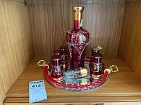 Full decanter set with 6 glasses on mirrored tray showing red glass with gold and white decoration