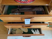 Partially open drawer showing various flatware including salad servers, cake servers, and silver utensils