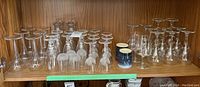 Shelf of various glassware including stemware and ceramic mugs