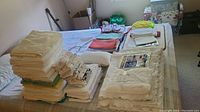 Image of several folded linens including towels and sheets stacked on a bed