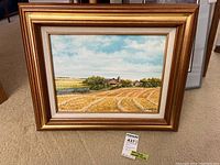 Frontal view of gold-tone framed oil painting depicting harvested field, barn, silo, pond under cloudy sky.