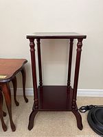 Front view of wooden stand with two shelves and turned supporting columns.