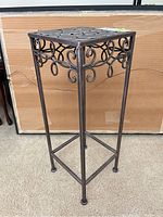 Full view of steel plant stand showing decorative scrollwork and flat top surface
