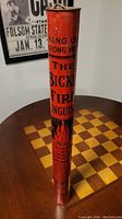 Full length cylindrical fire extinguisher with red body, black and red printed flame graphics and text reading 'The Bickle Fire Extinguisher'. The extinguisher has a hook on top for hanging and shows vintage wear.