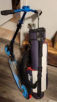 Photo showing blue Razor folding scooter and junior golf bag with clubs together on table.