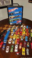 Photo showing Hot Wheels cars and the travel case on a table from above