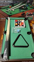 Tabletop pool table with cues, balls, rack, and box in packaging and ready to play.