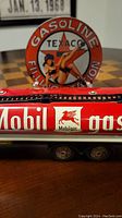 Close-up of the MobilGas tanker showcasing the red and white paint with Pegasus logo and partial view of the Texaco pinup sign in the background.