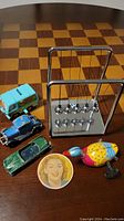 Photo of the entire lot on a table, showing toy cars, windup duck toy, BMW Newton's cradle, and pocket mirror.