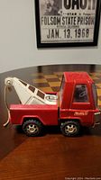 Side view of vintage Buddy L tow truck showing red body and white tow arm.