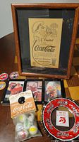 Framed vintage Coca-Cola advertisement, sealed marble pack, framed prints, 75th anniversary glass dish visible