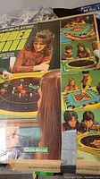 Photo shows the Coleco 199 Games Board box with images of people playing various games on the board, vintage style packaging with a woman and a boy playing.