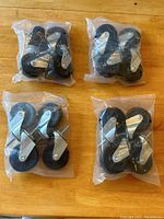 Four sets of caster wheels packaged in clear plastic bags, showing black wheels with metal frames and threaded stems.