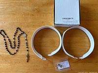 Overview image showing rosary, two white clergy collars, pair of chrome pileated studs in plastic bag, and a white box.