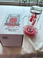 Photo of the glass hummingbird feeder next to its box on a white surface with a background window.