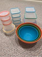 11 Snap Ware plastic food storage containers with varying sizes and color-coded lids, and 3 nested Nordic Ware plastic mixing bowls in red, orange, green, and blue.