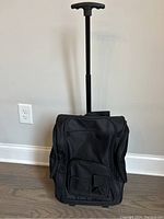 Front view of black rolling backpack with handle extended, showing compact and upright stance.