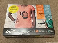 Front view of unopened Speedball Screen Printing Intermediate Kit box showing printed t-shirt example and product details.