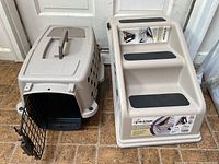 Photo of pet carrier with open wire door and adjacent plastic pet steps with black grip pads