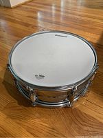 Top view of drum head showing Ludwig and Remo logos, white drumhead with metal tension rim and rods.