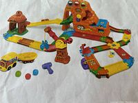 Full view of assembled VTech Treasure Mountain Train Adventure playset with track layout, mountain, train, and accessories including plastic marbles and a small purple tool.