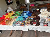 Wide view of 72 skeins and partial skeins of yarn arranged on table, displaying variety of colors and textures.