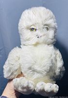 Front view of the white snowy owl plush toy held in hand showing detailed fur texture and facial features.