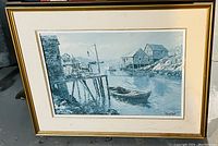 Framed print showing Peggy's Cove scene with buildings on water and a boat in foreground.