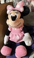 Front view of Minnie Mouse plush showing pink polka dot dress, bow, and black ears.