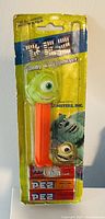 Front view of sealed Monster Inc. PEZ candy dispenser in original packaging showing Mike Wazowski character head and 3 PEZ candy rolls included.