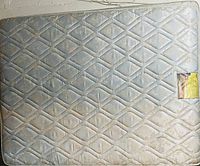Photo of queen size mattress showing quilted diamond and floral pattern with stains and a damaged patch exposing foam.