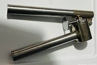 Garlic mincer shown from the side, highlighting long cylindrical handles and attached mincing chamber with hinged cover.