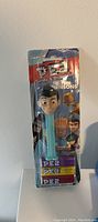 Photo of sealed PEZ dispenser with The Robinsons character head, three candy packs included, packaged with branded backing card.