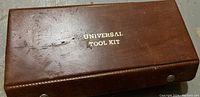Top-down photo showing the textured brown surface of the Universal Tool Kit box with gold printed label on top.