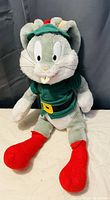 Photo showing a vintage Bugs Bunny plush toy dressed as an elf, highlighting the costume's colors and plush details.