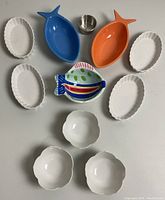 Overview of all dishes including fish-shaped, white oval scalloped dishes, flower-shaped cups, and metal ring seen from above