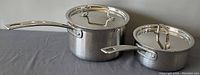 Two Cuisinart stainless steel sauce pans with lids; both pans have long handles and induction ready construction.