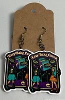 Pair of Easy Bake Coven Halloween-themed dangle earrings still attached to cardboard backing.