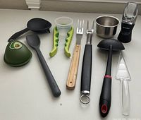 Photo of all items arranged on a white surface showing details and variety of kitchen and grill tools