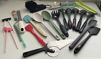 Top view of assorted kitchen utensils arranged horizontally on white surface.