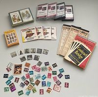 Photo showing assorted vintage postage stamps, five contract bridge score pads, one bridge instruction booklet by Charles H. Goren, four CD3 packs, Little Milton cards, Screen Legends cards, and a small box of cards.