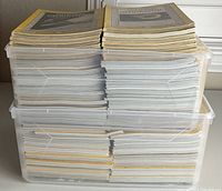 Stacked vintage National Geographic magazines in two clear plastic storage bins showing volume and condition