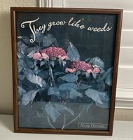 Framed artwork featuring two babies in berry costumes nestled amongst leaves, with the text "They grow like weeds" and Anne Geddes branding visible.